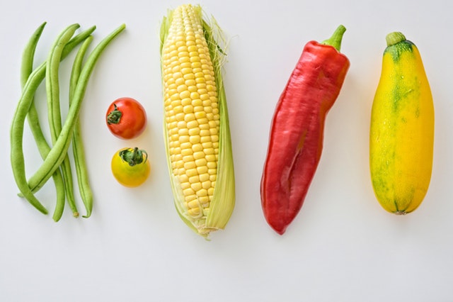 Fazuľové lusky, paprika, paradajky, kukurica a cuketa na bielom pozadí